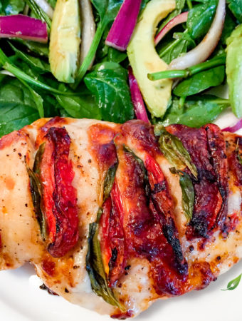 Hasselback Caprese Chicken with a fresh garden salad on a white plate