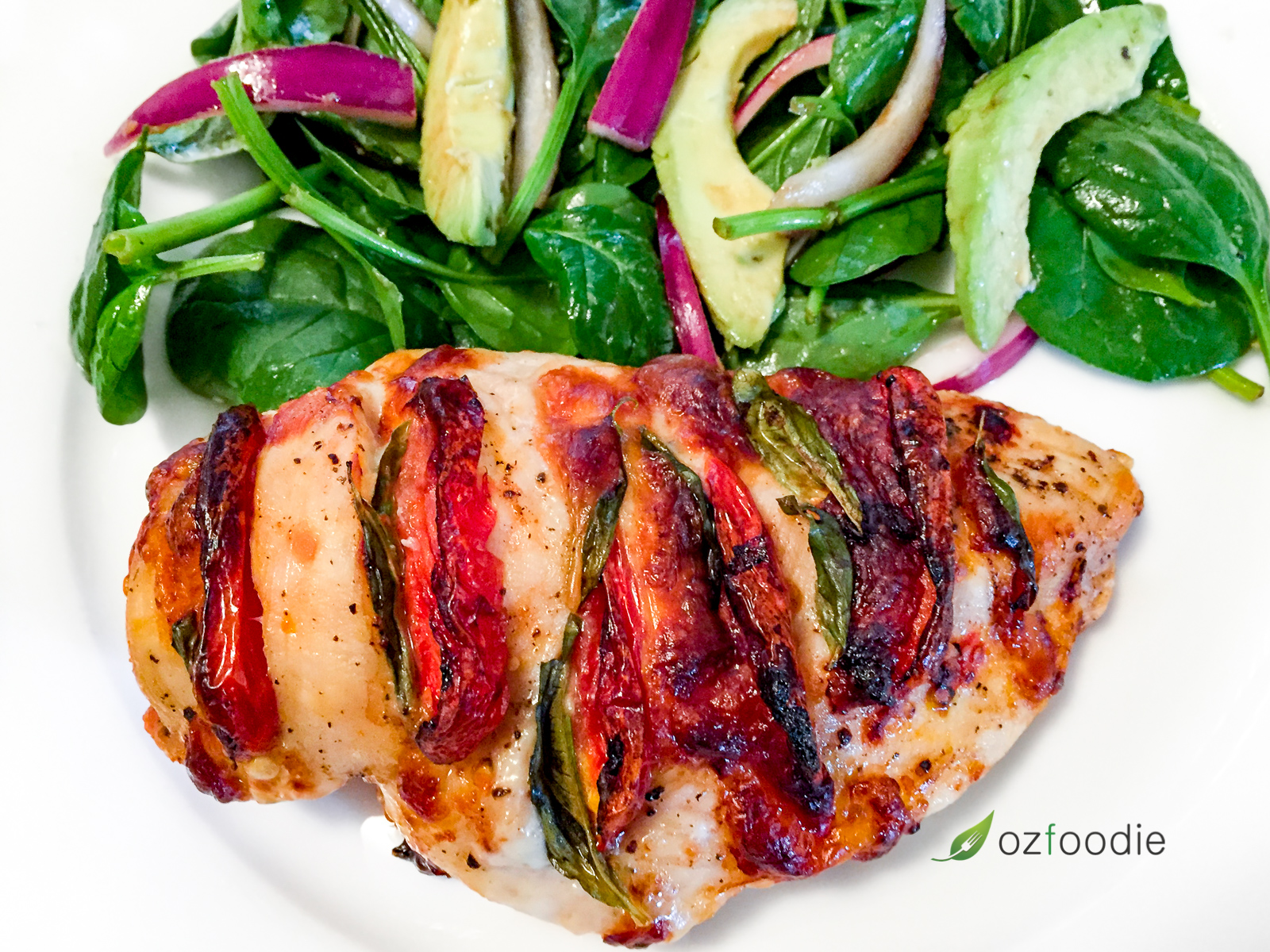 Hasselback Caprese Chicken with a fresh garden salad on a white plate